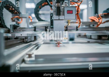 Automated laser cutting machine working on industrial sheet material. Precision laser cutting head processing sheet material on a modern automated pro Stock Photo