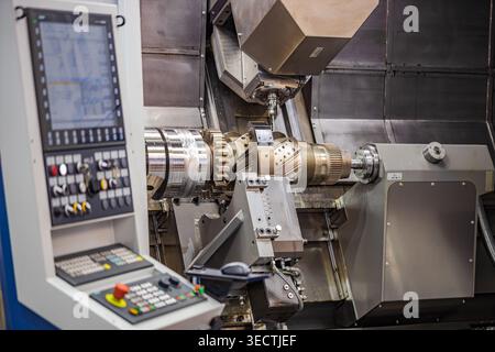 CNC milling machine machining large metal gear component in factory. Modern industrial CNC machine processing precision metal transmission part inside Stock Photo