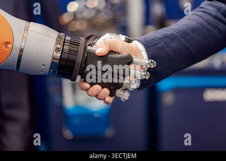 A businessman in a suit shaking hands with a modern robotic arm, symbolizing partnership, innovation and collaboration between humans and advanced tec Stock Photo