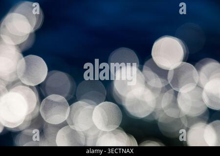 Soft diffuse light circles shimmer across a deep blue-black background, creating an elegant abstract backdrop with dreamy bokeh texture for copy use. Stock Photo