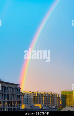 Beijing, China - May 02 2026: Vibrant rainbow over residential buildings and construction site during golden hour Stock Photo