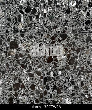 Black granite wall surface with smooth polished tiles, visible grout lines, and strong grey, white, and subtle amber vein patterns Stock Photo