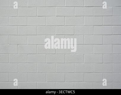Close up of painted white cinder block wall with rough coarse concrete blocks, smooth mortar grooves, long gouge in one block Stock Photo