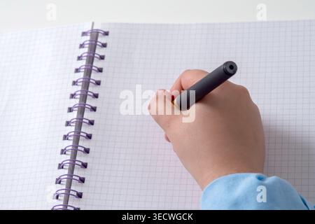 Hand grips pen poised over graph paper Stock Photo