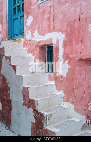 Pink cycladic facade with whitewashed stairs and blue door in Chora town, Mykonos island, Greece, Europe, showing traditional island architecture. Stock Photo