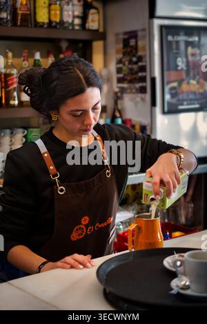 Smiling waitress preparing coffee and traditional snacks in a Spanish bar. Stock Photo