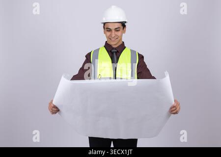 Young builder in helmet holding a large white blueprint Stock Photo