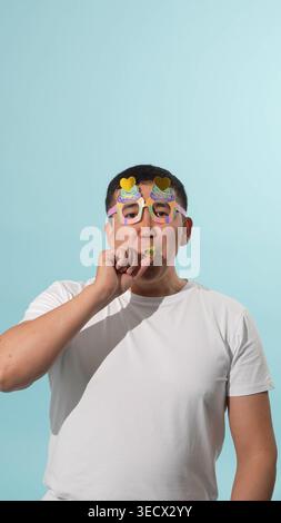 Young man in a party hat blowing a festive whistle Stock Photo