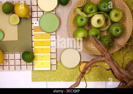 Vibrant flat lay composition featuring citrus fruits, kiwi, lemon and orange with color palette swatches, natural textures and tropical fan leaf. Stock Photo