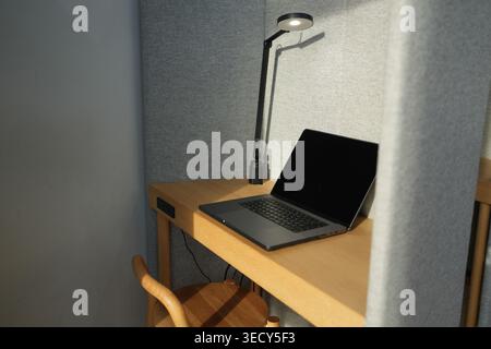 Cozy desk setup with laptop and focused task light. Warm wood tones create inviting workspace ambiance. Minimalist design suggests calm productivity o Stock Photo