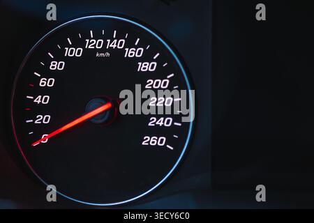 Illuminated car dashboard speedometer at night. Close up view of vehicle speed gauge in the dark. Stock Photo