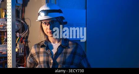 Electrical engineer standing near switchboard holding system blueprint. Professional portrait. Stock Photo