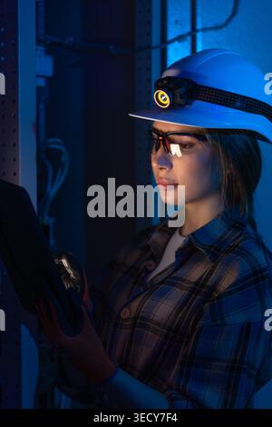 Electrical engineer inspecting power system with tablet near switchboard. Technical control. Stock Photo