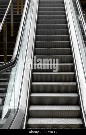 Close up of a moving escalator in a modern interior. Metallic texture and lines of motion. Stock Photo
