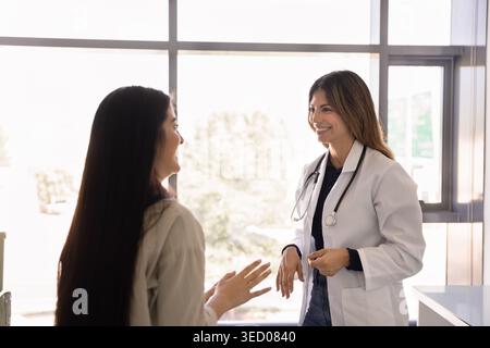 Young doctor and woman patient having friendly conversation in clinic Stock Photo