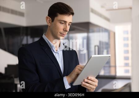 Well-dressed young businessman in suit interacts with tablet Stock Photo