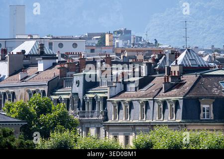 View over historic rooftops in Geneva with mountain backdrop and summer blue sky, Switzerland. Stock Photo