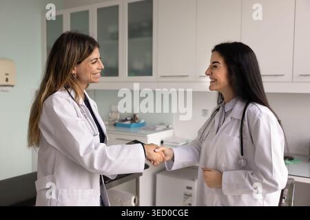 Two women doctors shaking hands standing in modern examination room Stock Photo