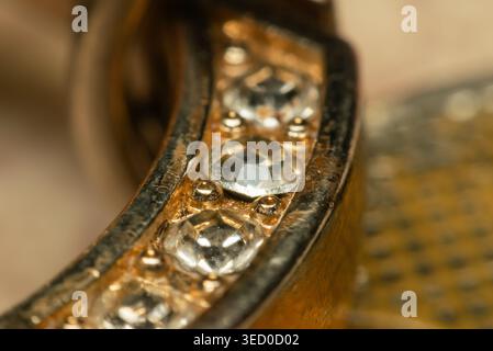 Close view of gold jewelry with clear crystal stones showing fine texture and sparkle under warm light elegant accessory detail with shallow depth of Stock Photo