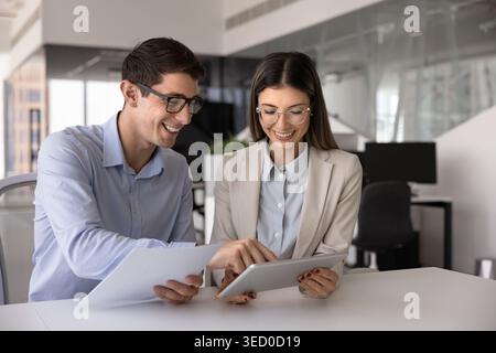 Colleagues using tablet, holding papers, working on joint project Stock Photo