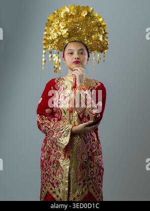 Portrait Of Indonesian Asian Woman In Traditional Red And Gold Wedding Dress With Ornate Ceremonial Headdress Stock Photo