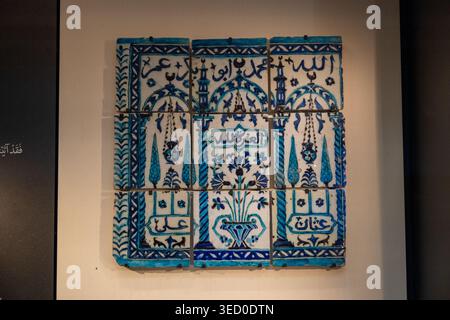 London, UK - 4 Jul 24: Blue-and-white Iznik ceramic tile panel with Arabic calligraphy and floral decoration, photographed on display at the British M Stock Photo