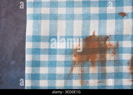 Checkered tablecloth with a stain on a dark surface Stock Photo