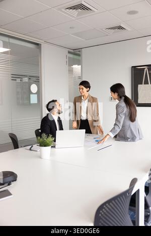 Multiethnic business team discussing charts and strategy in corporate boardroom Stock Photo
