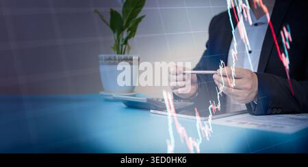 Professional corporate businessman or financial analyst in a suit sitting at a desk with a digital tablet, calculator, and printed reports. A double e Stock Photo