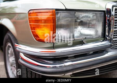 Close up detail of headlight, indicator, headlight wiper and chrome bumper on vintage luxury car. Retro automotive design with elegant lines and class Stock Photo