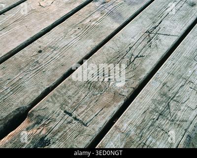Close-up of aged wooden deck boards with natural cracks and grain. Rustic texture ideal for backgrounds, construction themes, renovation concepts, or Stock Photo