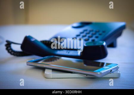 Evolution of communication technology featuring a modern smartphone and an analog office telephone, conceptual comparison of digital and traditional d Stock Photo
