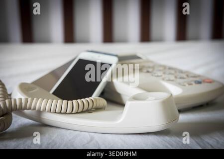 Evolution of communication technology featuring a modern smartphone and an analog office telephone, conceptual comparison of digital and traditional d Stock Photo