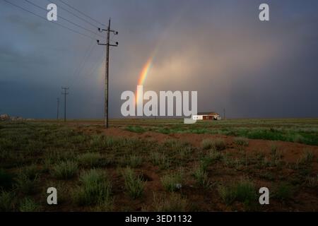 A vivid double rainbow arches on an open prairie, evoking rural solitude, weather drama, memory and quiet resilience after a passing storm in Kazakh s Stock Photo