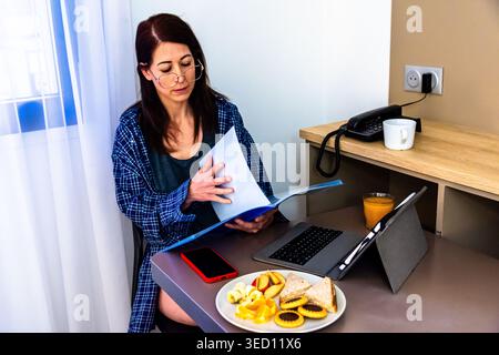 Woman working remotely from home office with breakfast Stock Photo