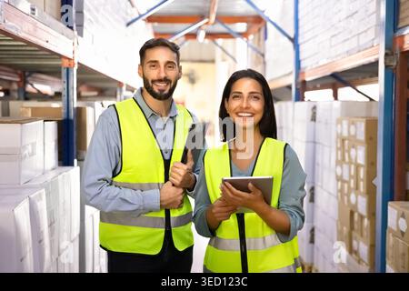 Warehouse workers standing in stockroom with digital tablet and clipboard Stock Photo