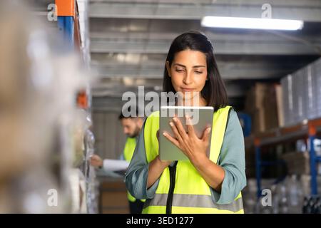 Female worker checking inventory with digital tablet in warehouse Stock Photo