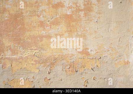Rough textured painted concrete wall with large patches of peeling paint Stock Photo