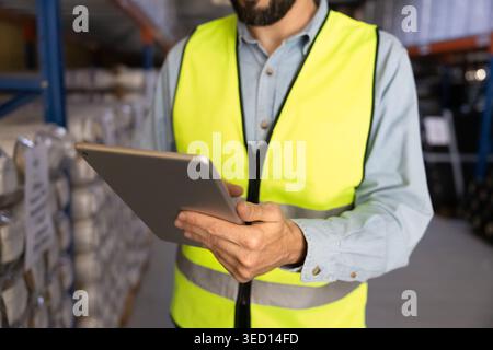 Worker using digital tablet for inventory management in warehouse facility Stock Photo