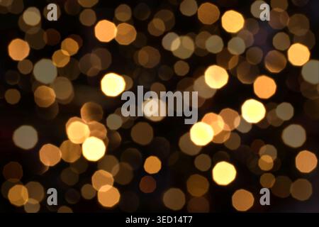 Warm yellow bokeh lights blurred on dark background creating abstract festive night atmosphere Stock Photo