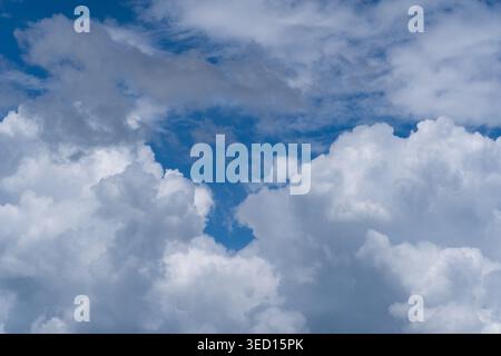 A high-resolution photograph of dramatic white cumulus clouds with deep gray shadows set against a vast, deep blue sky. The image captures the dynamic Stock Photo