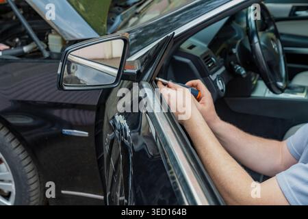 Owner assesses damage. Inspecting car scratch details. Owner carefully inspects damage on vehicle panel. Individual examines extensive scratch on car Stock Photo