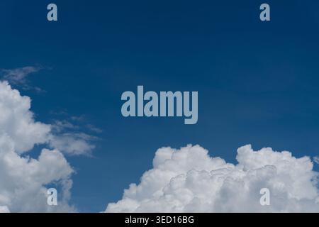 A high-quality nature photograph featuring dense, bright white cumulus clouds positioned predominantly along the bottom and left side of the frame. Th Stock Photo