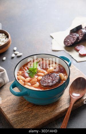 Asturiana Spanish traditional fabada stew with haricot, blood sausage on brown background. Vertical orientation. Stock Photo