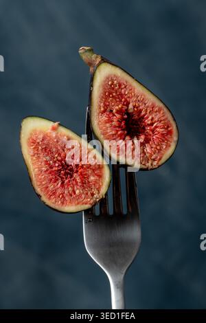 Close view of sliced fig resting on a fork in studio light Stock Photo