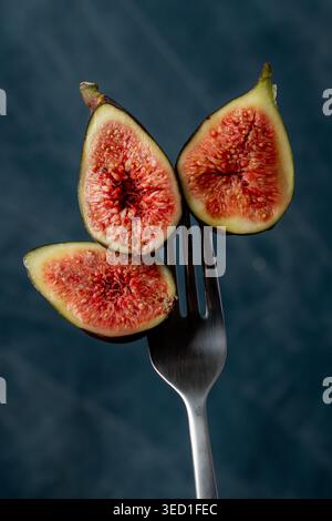 Slices of fresh figs displayed on a fork with dark backdrop. Stock Photo
