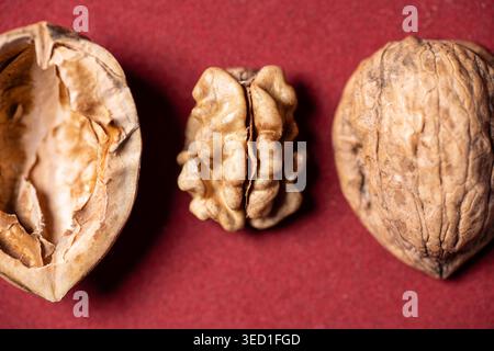 Walnuts display their shells and kernels on a red background. Stock Photo