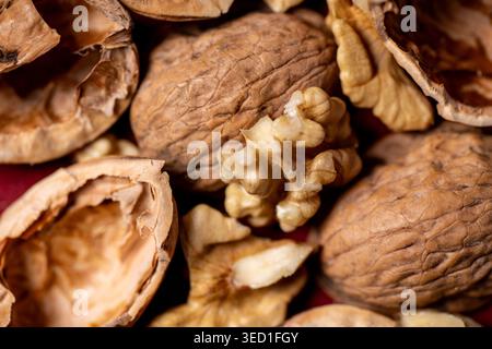 Shells of walnuts surround the nut on a red surface. Stock Photo