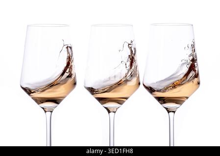 Three glasses showcase swirling wine against a white background. Stock Photo