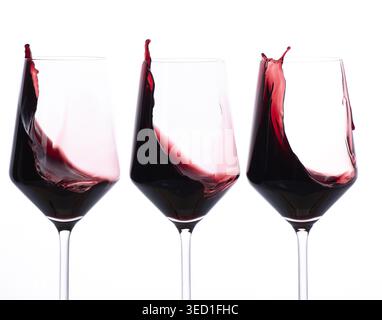 Red wine splashes in glasses, showcasing its flow. Stock Photo